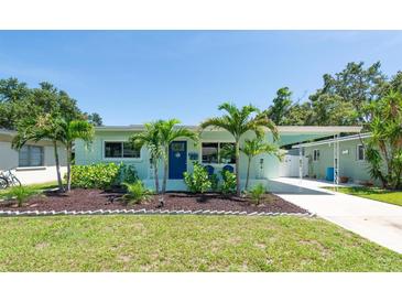 Charming, light-blue single Gathering home featuring lush landscaping, a well-manicured lawn, and a covered carport at 4718 24Th S Ave, St Petersburg, FL 33711