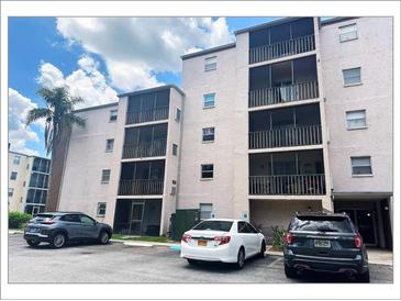 Condo building with large screened balconies in a tropical community near parking and entry at 5541 Bay Blvd # 303, Port Richey, FL 34668