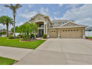 Inviting two-story home with a three-car garage, lush landscaping, and a grand entryway at 13728 Artesa Bell Dr, Riverview, FL 33579