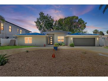 Charming home with a gray exterior, circular driveway, and manicured landscaping at 2650 W Bay Isle Se Dr, St Petersburg, FL 33705