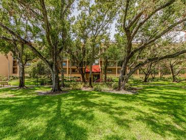 Beautiful exterior view of a multi-story building nestled among lush trees and green lawn, creating a serene environment at 3078 Eastland Blvd # 205, Clearwater, FL 33761