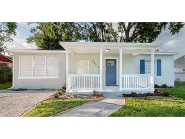 Charming home with a blue front door, white railing, and a walkway through the landscaped front yard at 3907 W Walnut St, Tampa, FL 33607