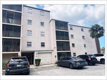 View of building exterior featuring screened balconies, white stucco and adjacent parking with a garage at 5541 Bay Blvd # 410, Port Richey, FL 34668