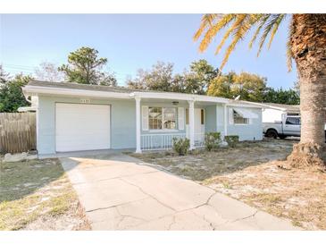 Charming single-story home with a light blue exterior, an attached garage, and a well-manicured front yard at 1131 Dartmouth Dr, Holiday, FL 34691