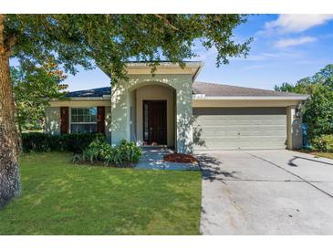 Charming single-story home featuring a manicured lawn, arched entryway and a two car garage at 1280 Hill Flower Dr, Brooksville, FL 34604