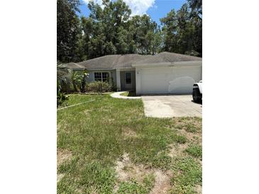 Charming single-story home with a two-car garage and a well-maintained lawn surrounded by mature trees at 14332 Sorrel St, Brooksville, FL 34614