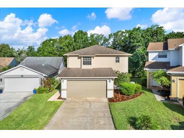 Charming two-story home with a well-manicured lawn and attached two-car garage on a beautiful sunny day at 6439 Gentle Ben Cir, Wesley Chapel, FL 33544