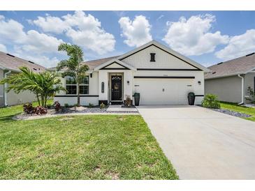 Charming single-story home featuring a two-car garage, manicured lawn, and decorative landscaping at 9028 Forge Breeze Loop, Wesley Chapel, FL 33545