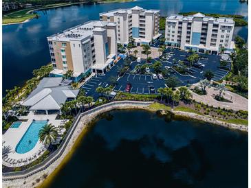 Stunning aerial view of condo buildings, pool, parking, and lakefront scenery, showcasing the community's amenities at 10520 Boardwalk Loop # 202, Bradenton, FL 34202
