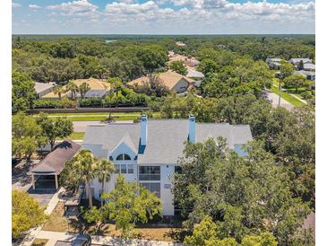 Beautiful condo featuring white exterior and gray roof, nestled among trees in lush landscaping at 3301 Haviland Ct # 301, Palm Harbor, FL 34684