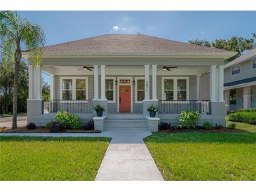 Charming home featuring a welcoming front porch, landscaped yard, and classic architectural details under a clear blue sky at 3811 N Arlington Ave, Tampa, FL 33603