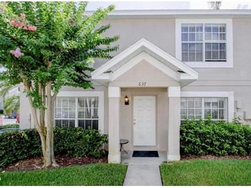 Charming townhome entrance with landscaped bushes, a flowering tree and a white door at 637 Kensington Lake Cir, Brandon, FL 33511