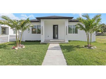 A charming home features a walkway leading to the front door, a lush lawn, and palm trees adding to the curb appeal at 711 42Nd S Ave, St Petersburg, FL 33705