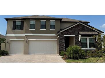 Beautiful two-story home featuring a two-car garage, stone accents, and manicured landscaping at 8922 Little Bluestem Dr, Land O Lakes, FL 34637