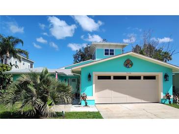 Charming turquoise home featuring a well-maintained lawn, two-car garage, and a lovely color scheme at 1626 Sea Breeze Dr, Tarpon Springs, FL 34689