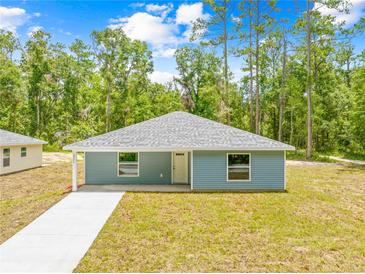 Charming single-story home featuring light blue siding and a well-manicured lawn at 19275 Wildwood Dr, Brooksville, FL 34601