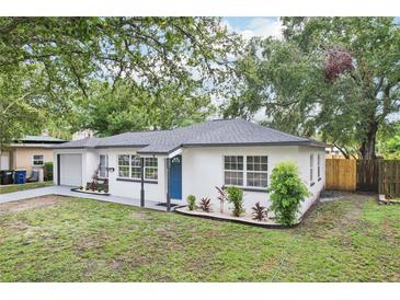 Charming single-story home with white exterior, blue front door, well-manicured lawn, and nicely landscaped front garden at 6 N Orion Ave, Clearwater, FL 33765