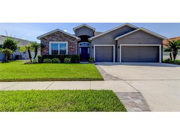 Charming single-story home featuring a well-manicured lawn, a two-car garage and stone facade accents at 6648 Castle Green Pl, Zephyrhills, FL 33541