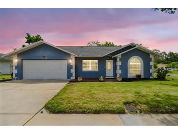 Charming single-story home featuring a well-manicured lawn, blue exterior, and a two-car garage at 8823 Aruba Ln, Port Richey, FL 34668