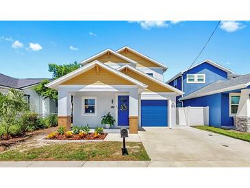 Charming home featuring a colorful front door, landscaped yard, and a one car garage at 2918 N 21St St, Tampa, FL 33605
