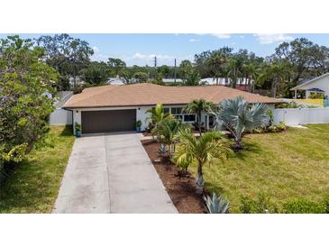 Charming single-story home featuring a well-manicured lawn, a long driveway, and a 2-car garage at 309 Palmetto Ln, Largo, FL 33770