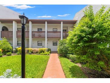 Inviting condo exterior featuring a well-maintained lawn and pathway to the entrance at 7614 Radcliffe Cir # 202B, Port Richey, FL 34668