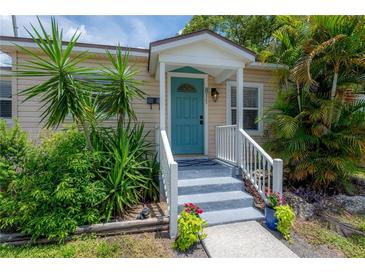 Charming home featuring a blue front door, well-kept landscaping, and inviting entrance steps at 811 W Peninsular St, Tampa, FL 33603
