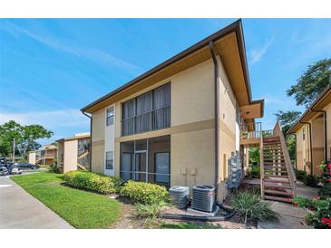Exterior of a two story condo building featuring a screened porch and manicured landscaping under a clear blue sky at 10195 Sailwinds N Blvd # 208, Largo, FL 33773