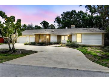 Charming one-story home with white siding, a spacious driveway, and lush landscaping at dusk at 10265 130Th St, Largo, FL 33774