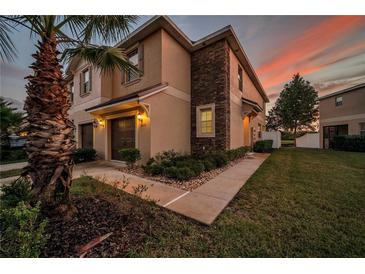 Two-story home featuring a stucco exterior, stone accents, attached garage, and landscaped yard at 12025 Greengate Dr, Hudson, FL 34669