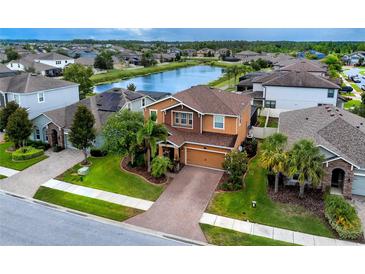 Beautiful two-story home boasts mature landscaping, brick driveway, and serene water views at 1601 Fox Grape Loop, Lutz, FL 33558