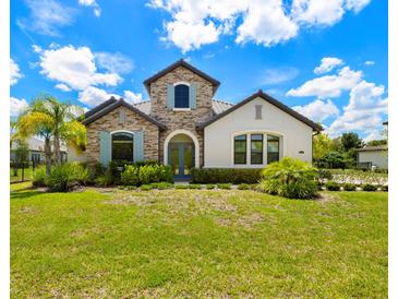 Charming two-story home with a stone facade, arched entryway, blue shutters, and a well-manicured front lawn at 2839 Cordoba Ranch Blvd, Lutz, FL 33559