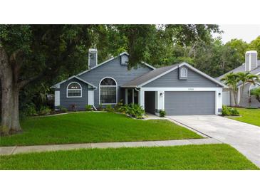 Charming gray home features manicured lawn, two-car garage, and mature trees at 7320 Hideaway Trl, New Port Richey, FL 34655