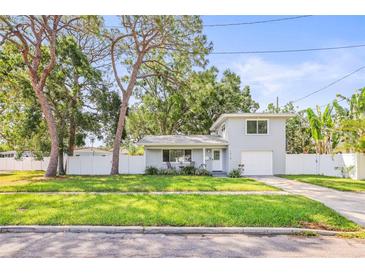 Charming two-story home featuring a manicured lawn, a white fence and a single car garage at 1518 Cheyenne Ne St, St Petersburg, FL 33703
