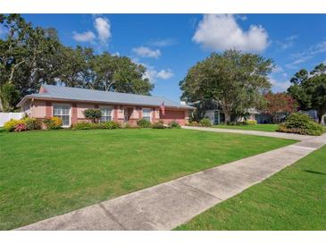 Charming single-story home with manicured lawn, mature trees, and metal roof at 15316 Winding Creek Dr, Tampa, FL 33613