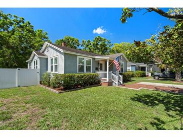 Charming bungalow with tidy lawn, brick pathway, and inviting front porch flying the US flag at 702 W Kentucky Ave, Tampa, FL 33603