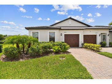 Charming home featuring a well-manicured lawn, a brick driveway, and a two-car garage at 10282 Echo Dock Loop, San Antonio, FL 33576