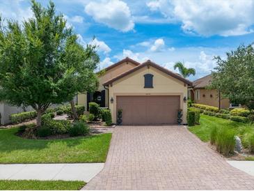 Charming single Gathering home featuring lush landscaping and a brick driveway and a two-car garage at 10450 Highland Park Pl, Palmetto, FL 34221