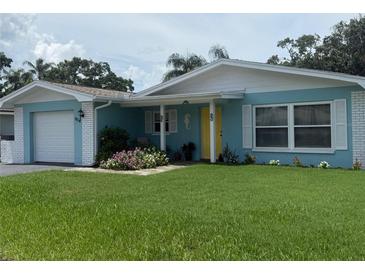 Charming, single-story home with a yellow door and well-manicured front lawn and garden at 1814 Driftwood S Cir, Oldsmar, FL 34677