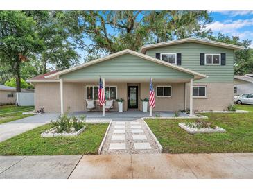 Inviting two-story home with a charming covered front porch, landscaped yard, and an American flag at 205 W Wheeler Rd, Seffner, FL 33584