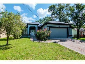 Charming single-story home featuring a well-manicured lawn, attached garage, and inviting front entrance at 211 Arlington E Ave, Oldsmar, FL 34677