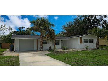 Charming single-story home featuring a driveway, garage, palm trees, and fresh landscaping at 2837 Woodcrest Dr, Sarasota, FL 34239