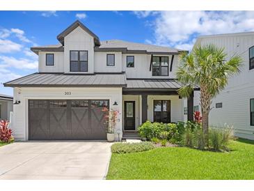 Charming two-story home features a landscaped yard, a garage, and a welcoming front porch at 303 N Beverly Ave, Tampa, FL 33609
