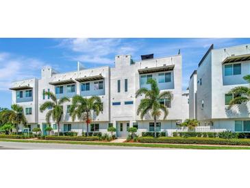 Modern townhome complex featuring a clean white facade and lush landscaping, under a clear blue sky at 3100 W Paul Ave # 15, Tampa, FL 33611