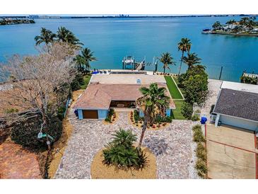 Waterfront home featuring lush landscaping, a private dock, and a brick driveway at 4381 Poinsettia Dr, St Pete Beach, FL 33706