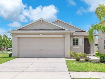 Charming single-story home featuring a two-car garage, neutral paint, and a well-manicured lawn at 4902 Grist Mill Ct, Wimauma, FL 33598