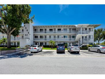 Condominium building with parking and multiple balconies under a clear blue sky at 8584 111Th St # 308, Seminole, FL 33772