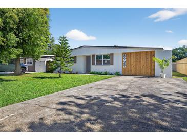 Charming home featuring a modern design, mature trees, a well-manicured lawn, and unique wooden architectural details at 8939 90Th Ave, Seminole, FL 33777