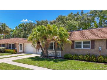 Charming home featuring a stone facade, well-maintained lawn, mature landscaping, and a lovely tile roof at 1102 Cara Dr, Largo, FL 33771