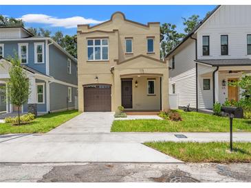 Inviting home featuring a well-manicured lawn, covered porch, and a charming two-story design with a private garage at 115 W Hiawatha St, Tampa, FL 33604